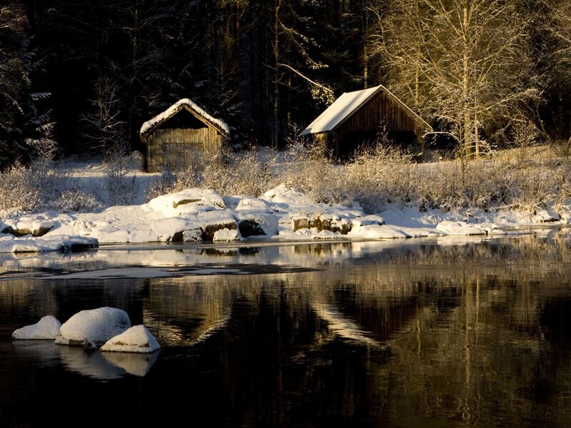 Snowy cabins by a river