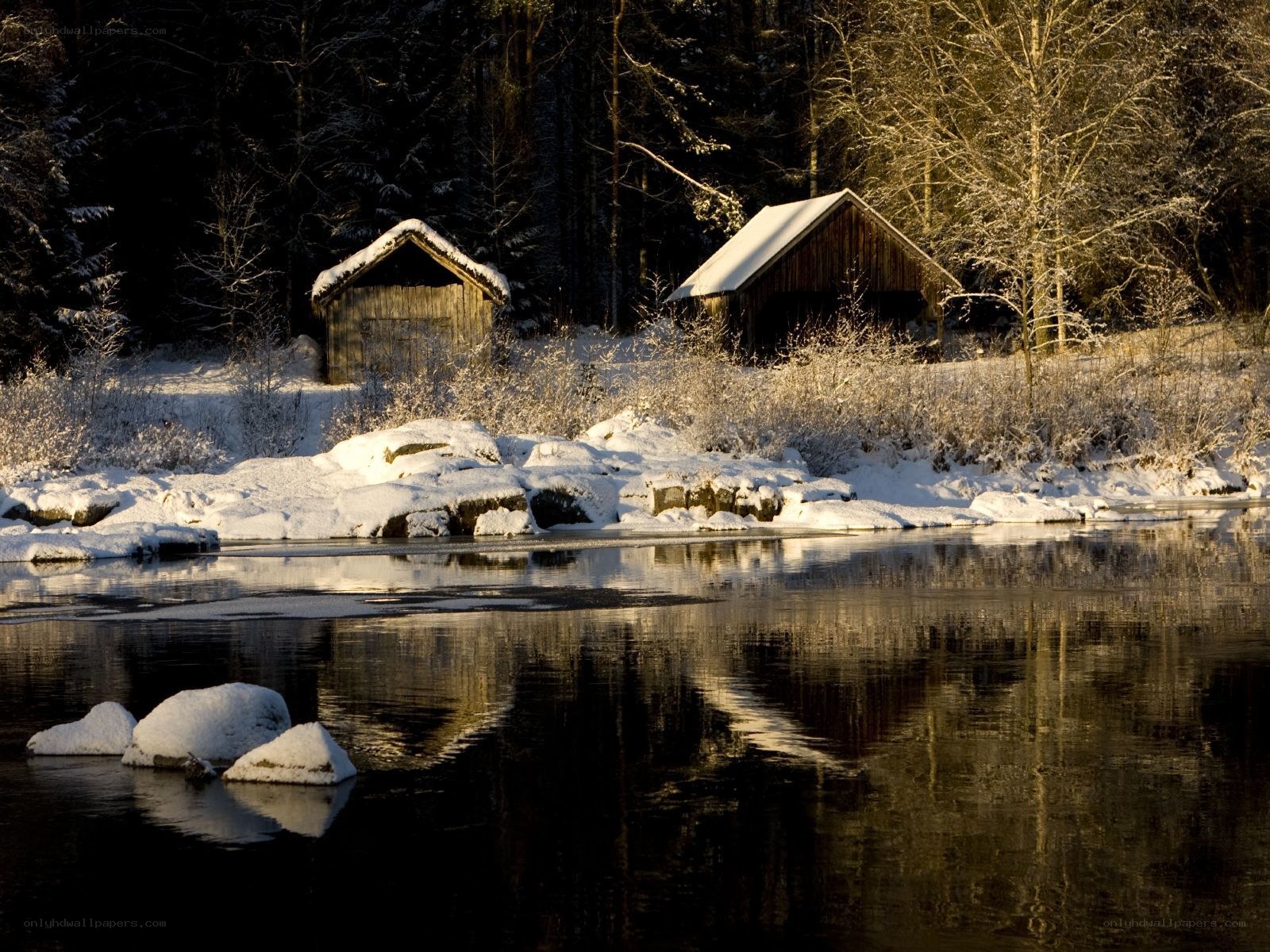 Snowy cabins by a river