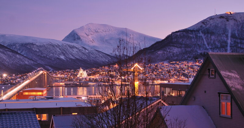 Snowy city at dusk with illuminated bridge
