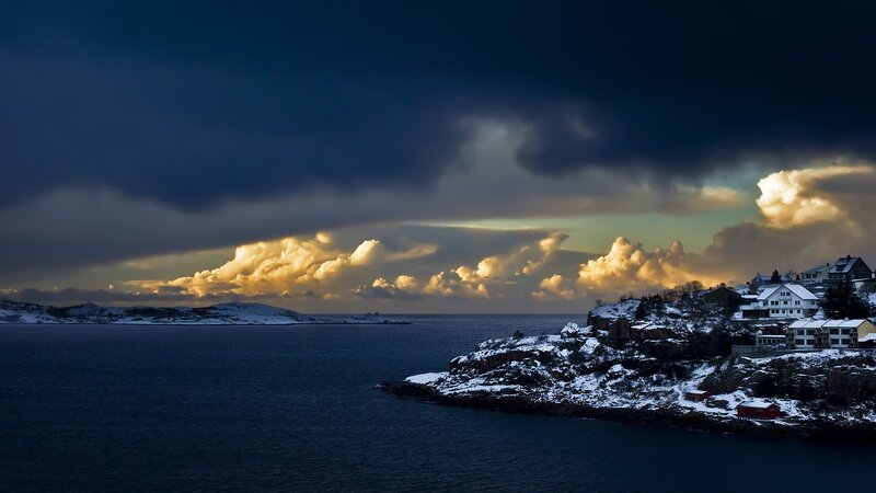 Snowy coastal village at sunset