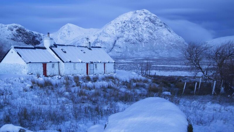Snowy cottage in mountain landscape