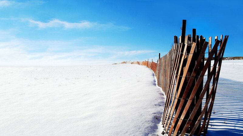 Snowy dune with wooden fence