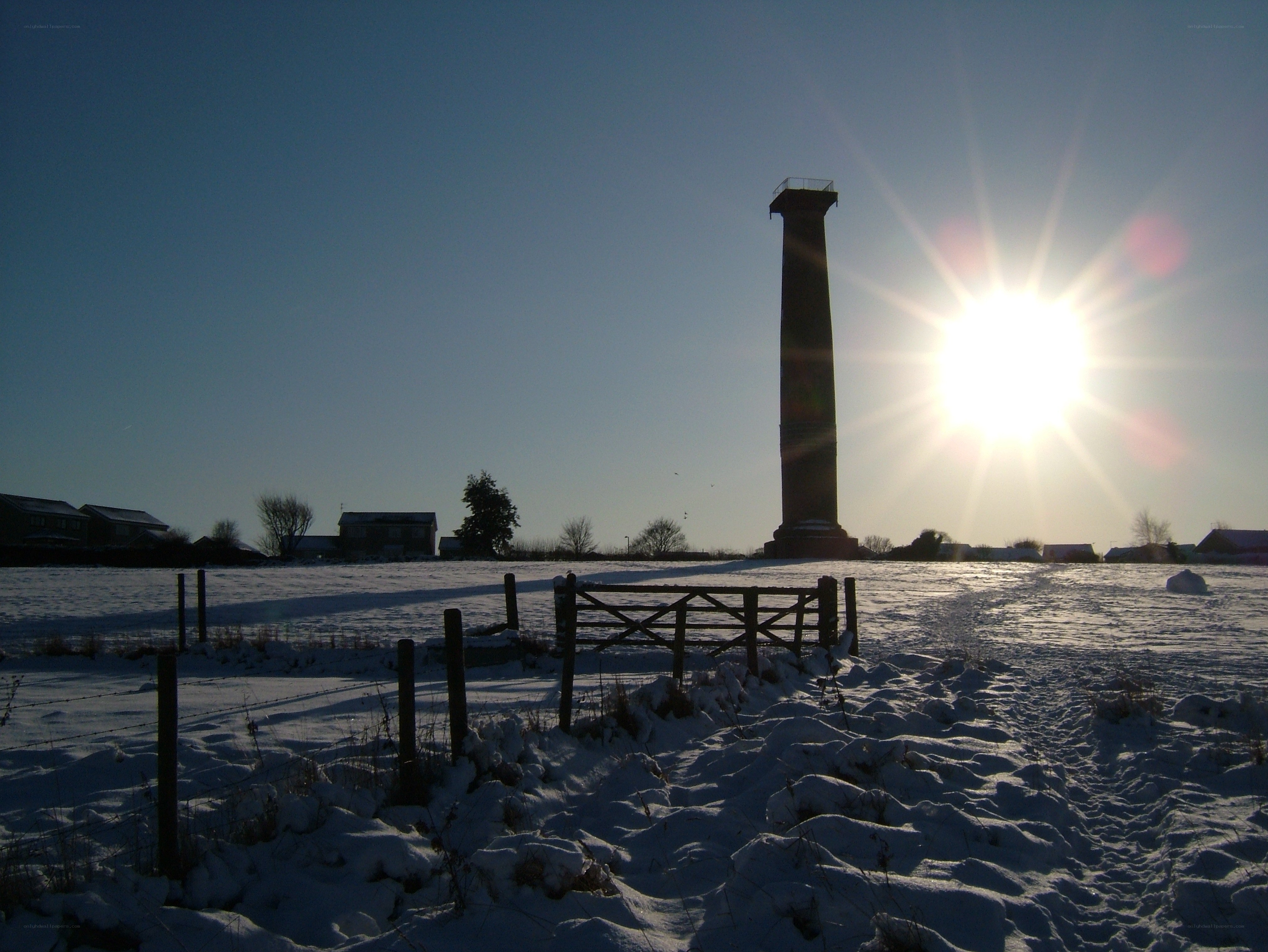 Snowy field with monument at sunset