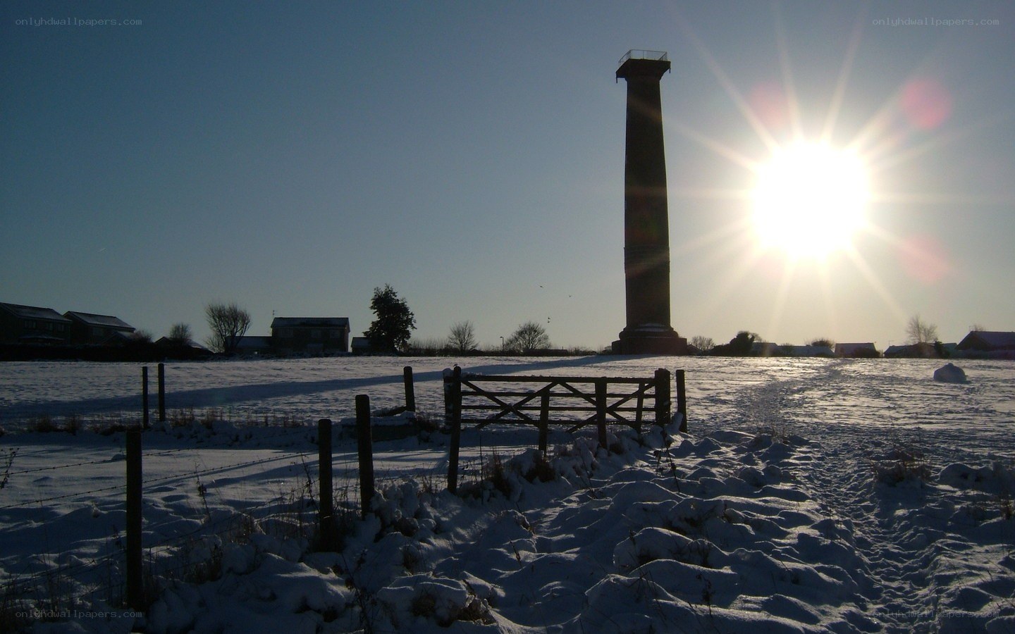 Snowy field with monument at sunset