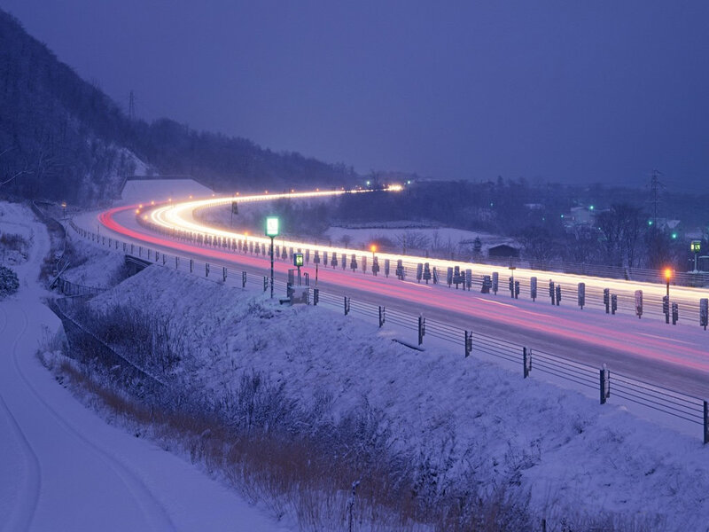 Snowy highway at night with light trails
