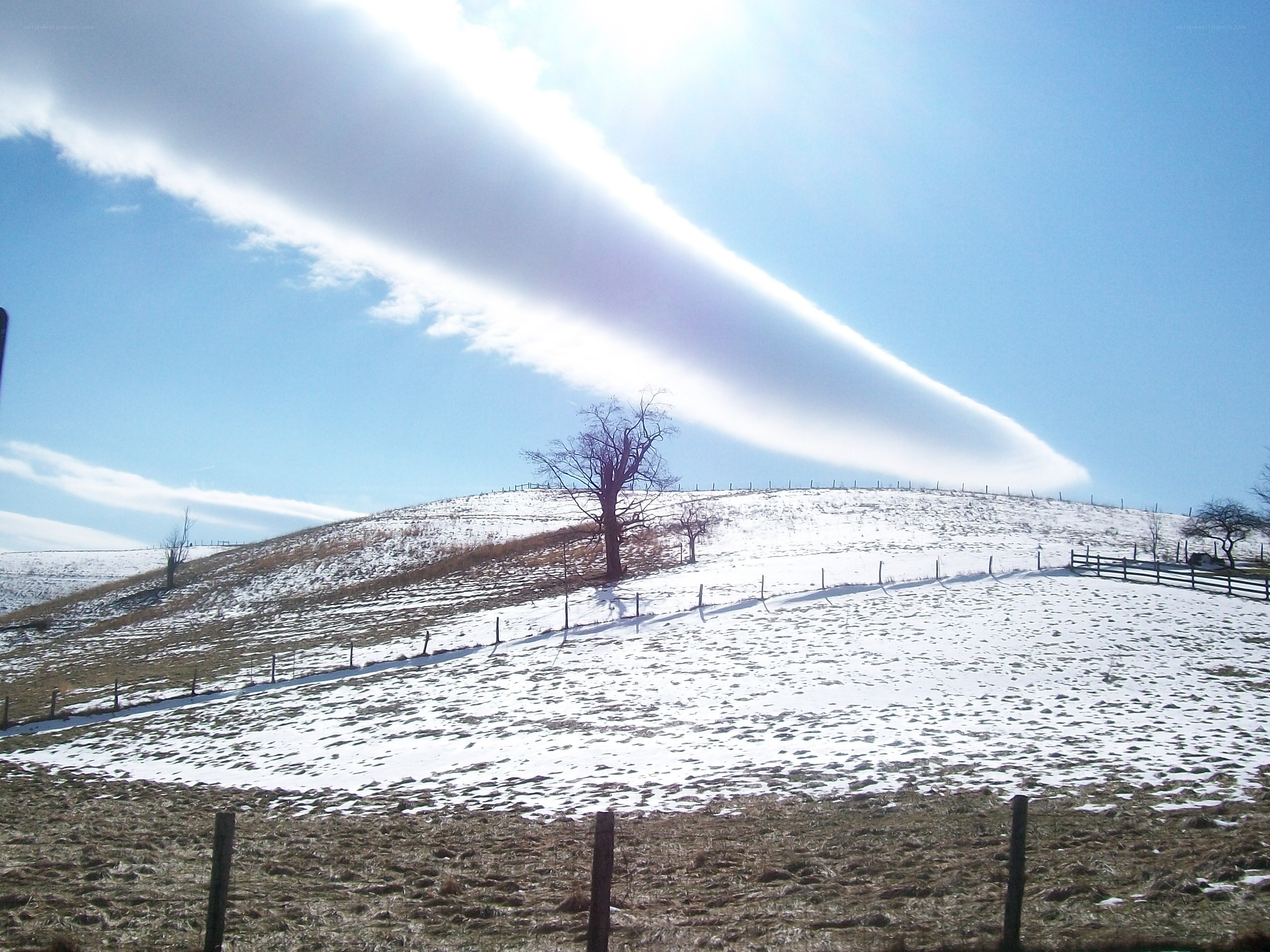 Snowy hill with lenticular cloud