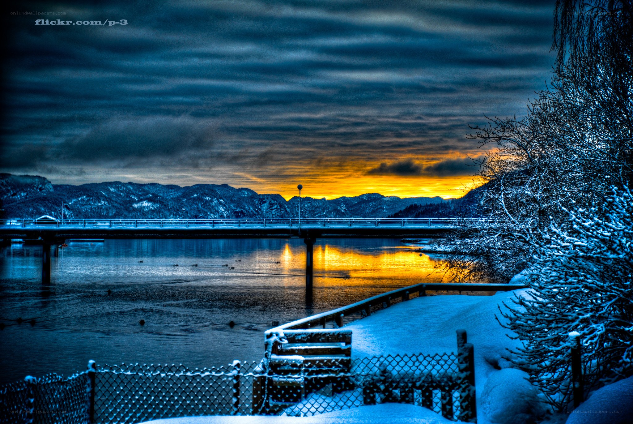 Snowy lake at sunset with bridge