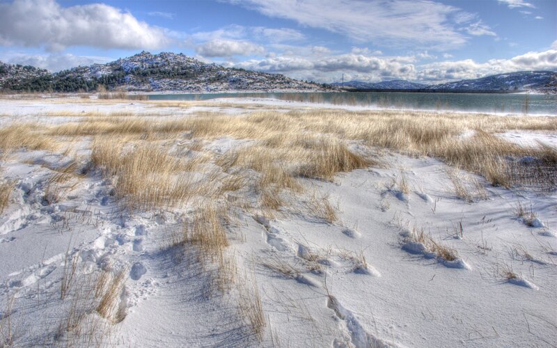 Snowy lake with grass and hills