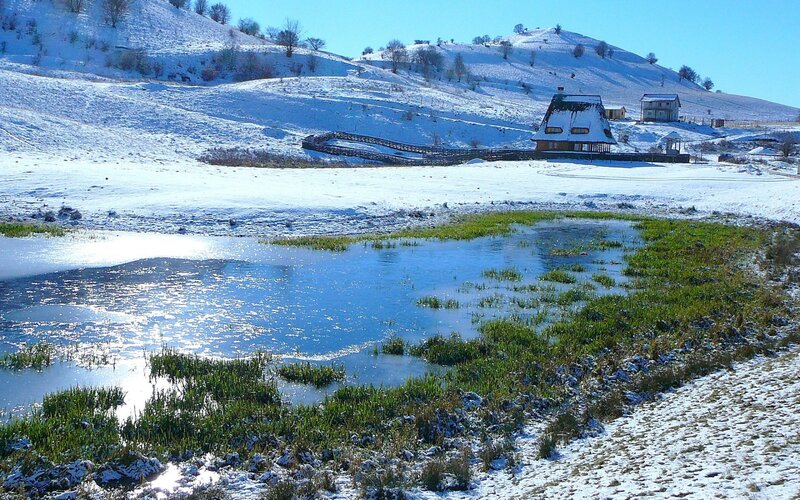 Snowy landscape with pond and house