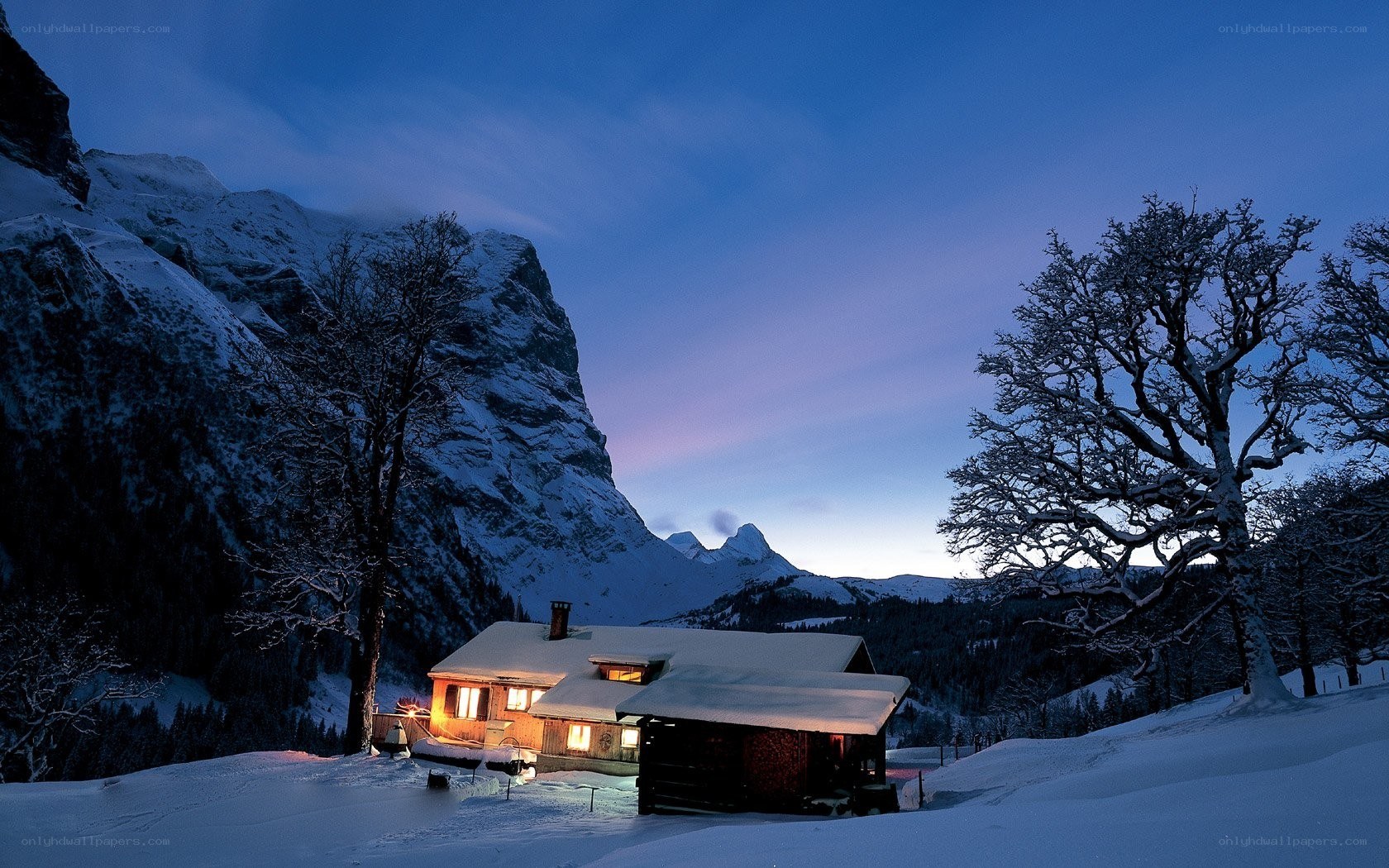 Snowy mountain cabin at dusk