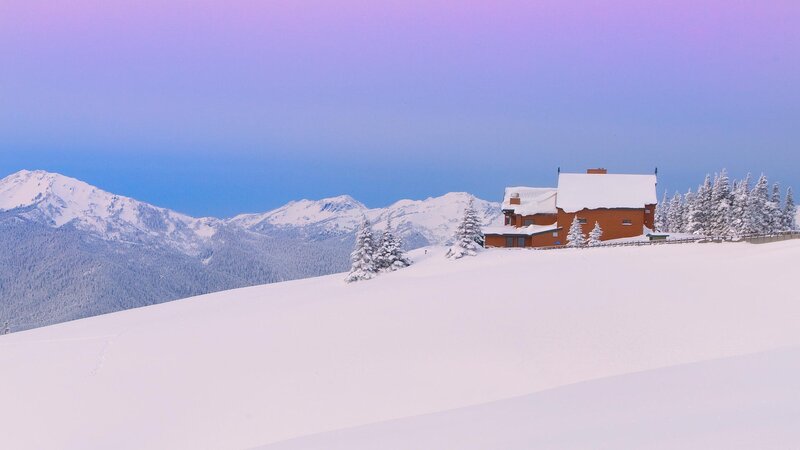 Snowy mountain cabin at dusk