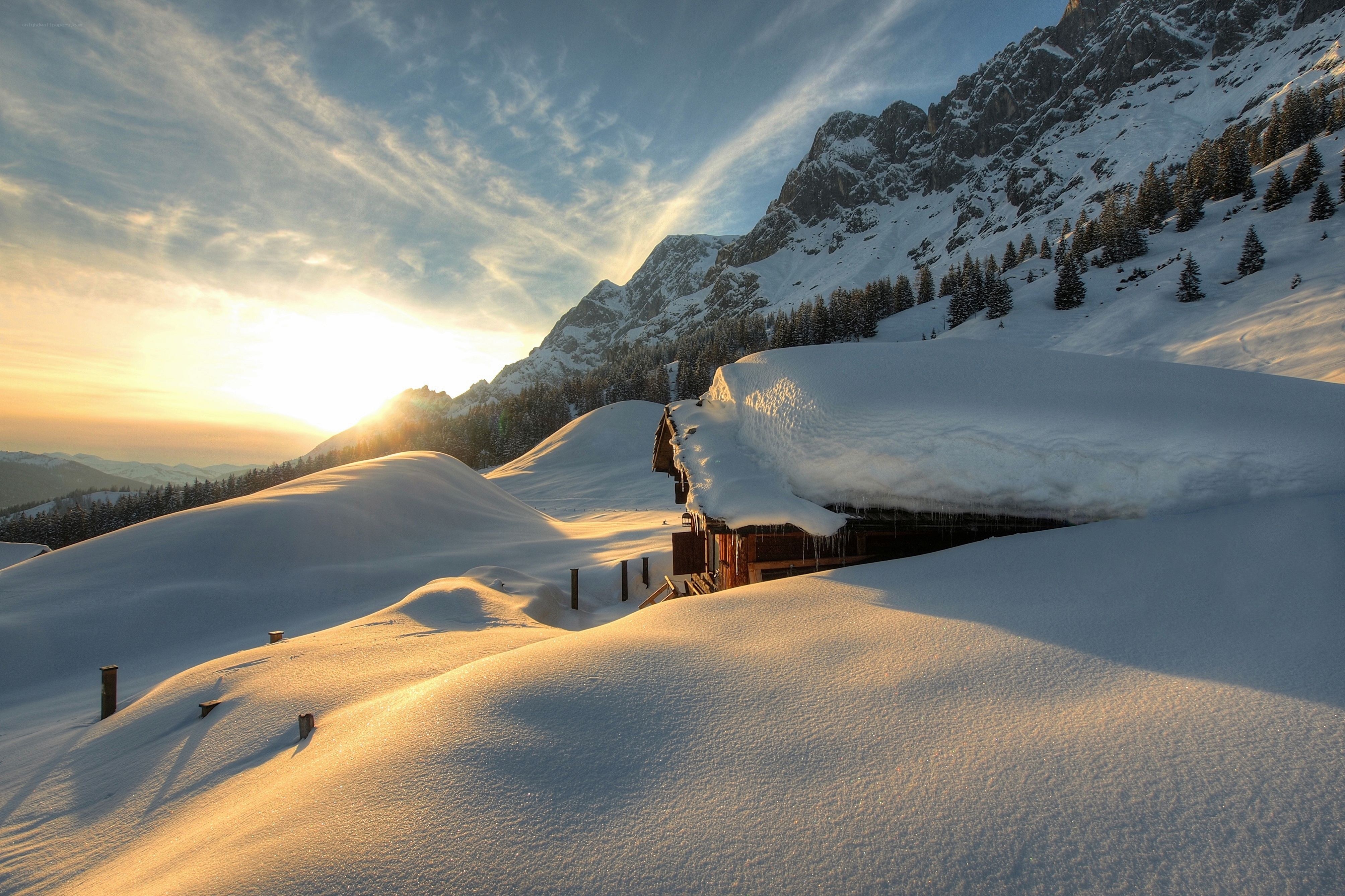 Snowy mountain cabin at sunset