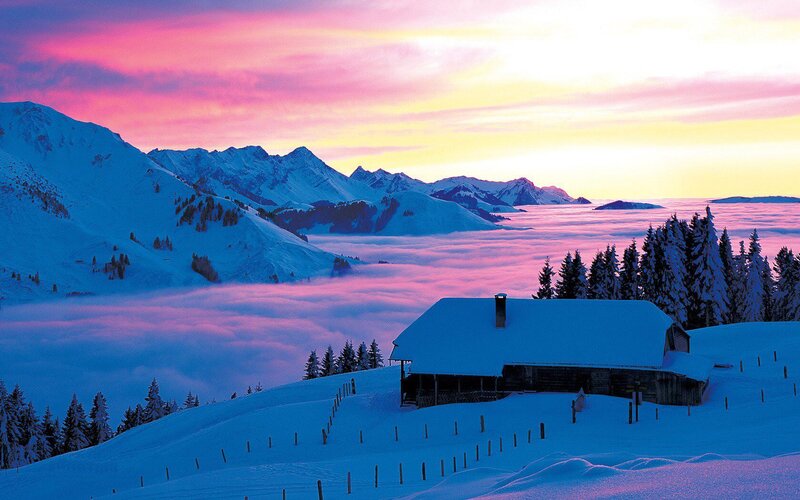 Snowy mountain cabin at sunset