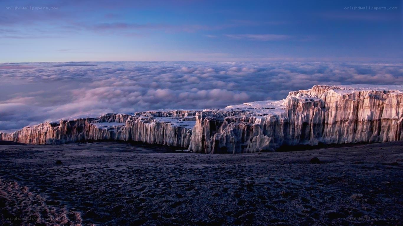 Snowy mountain cliffs above clouds