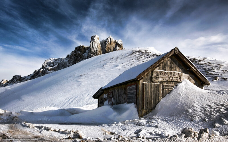 Snowy mountain hut with rocky peak