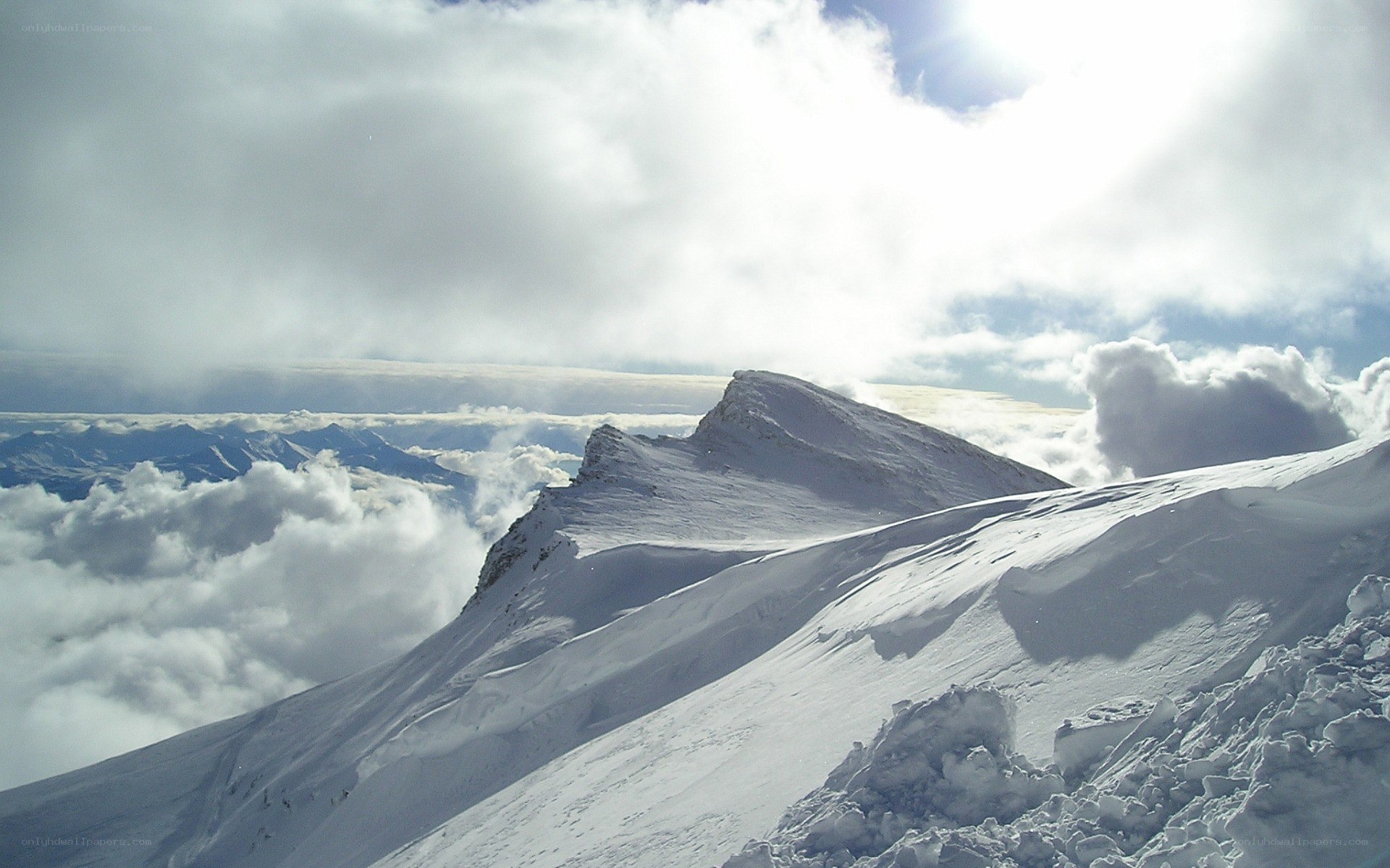 snowy mountain peak above clouds
