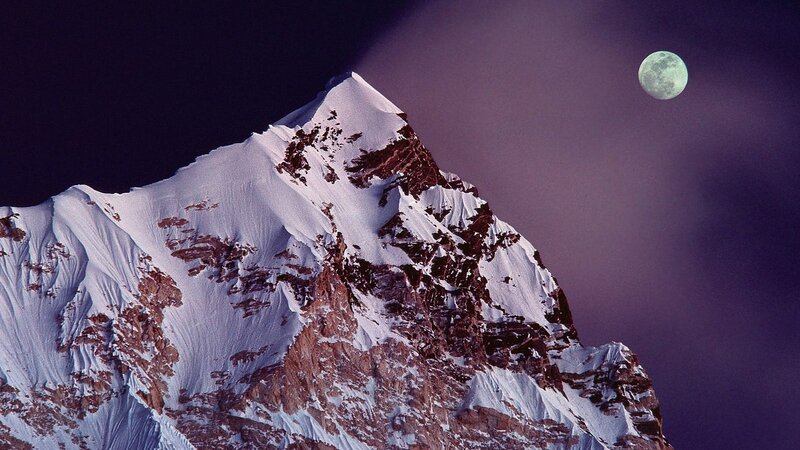 Snowy mountain peak under moonlight