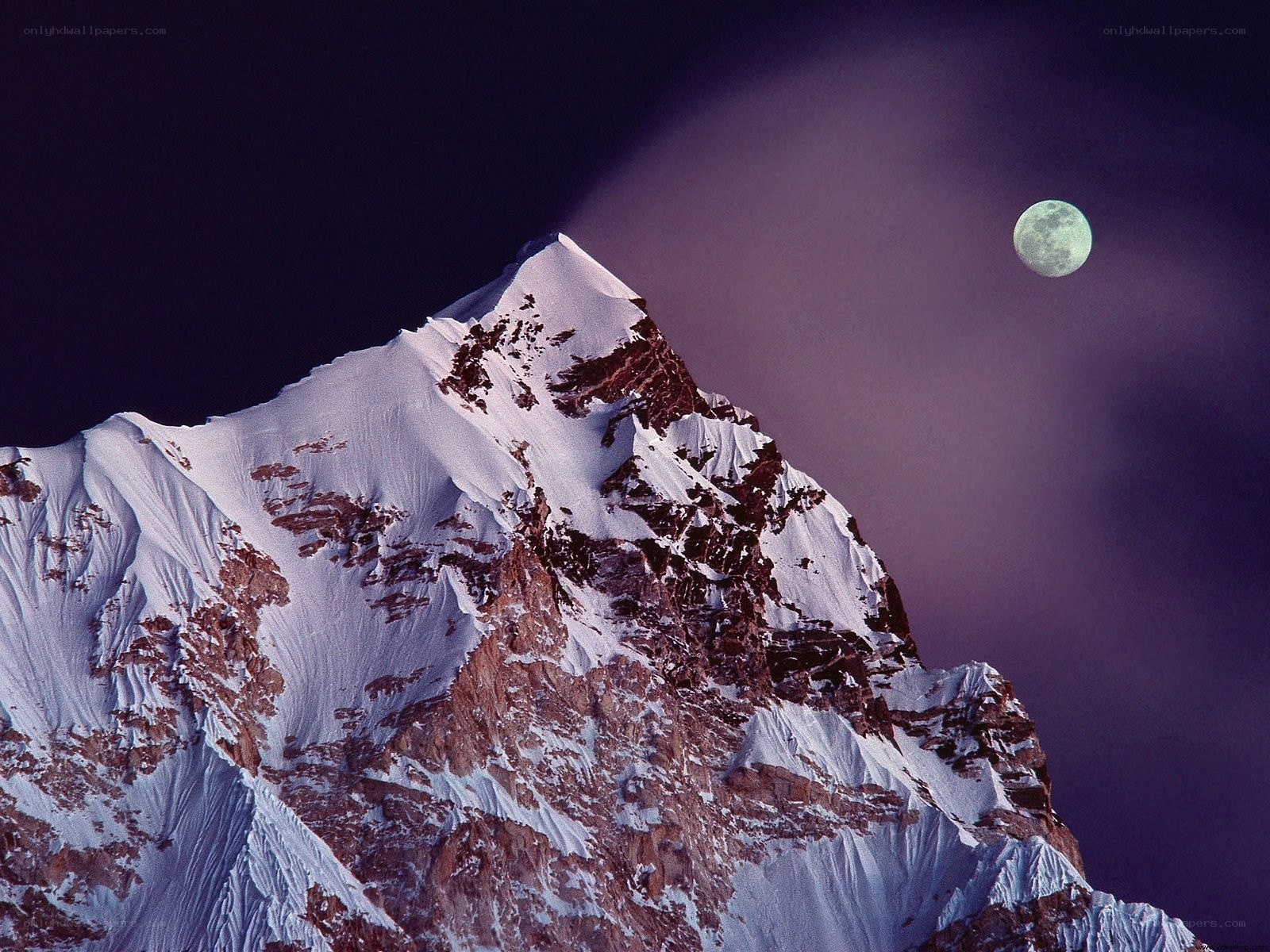 Snowy mountain peak under moonlight