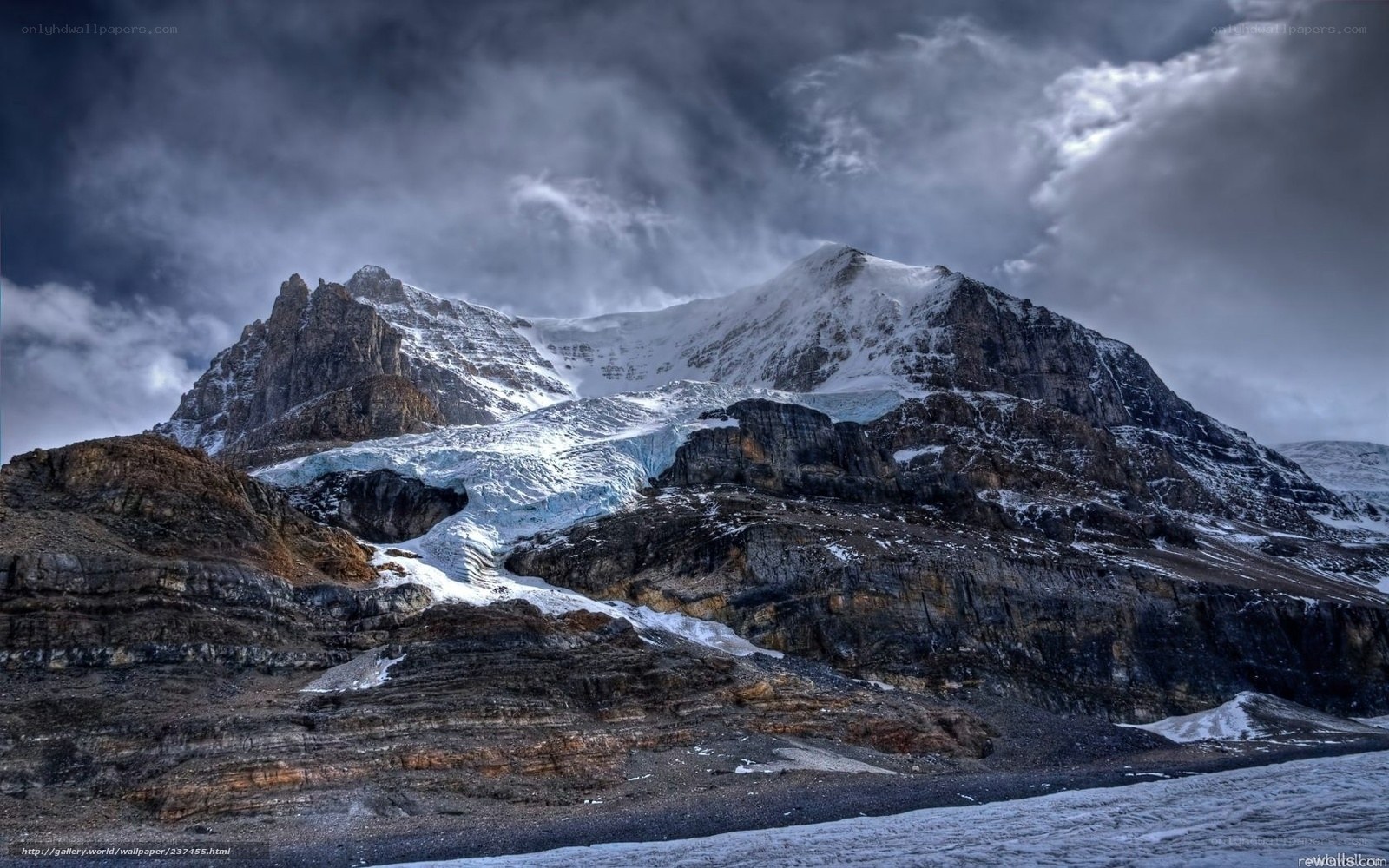 Snowy mountain peak under stormy sky