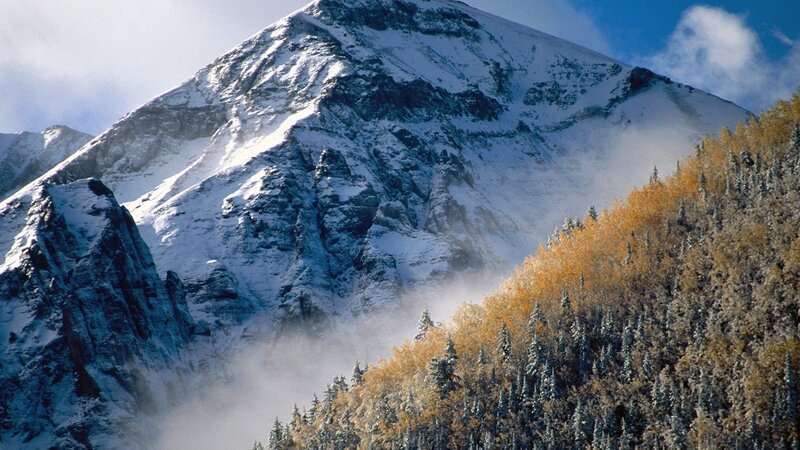 Snowy mountain peak with autumn trees