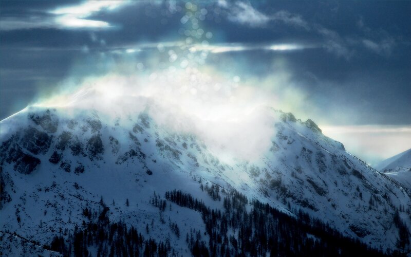 Snowy mountain peak with light rays