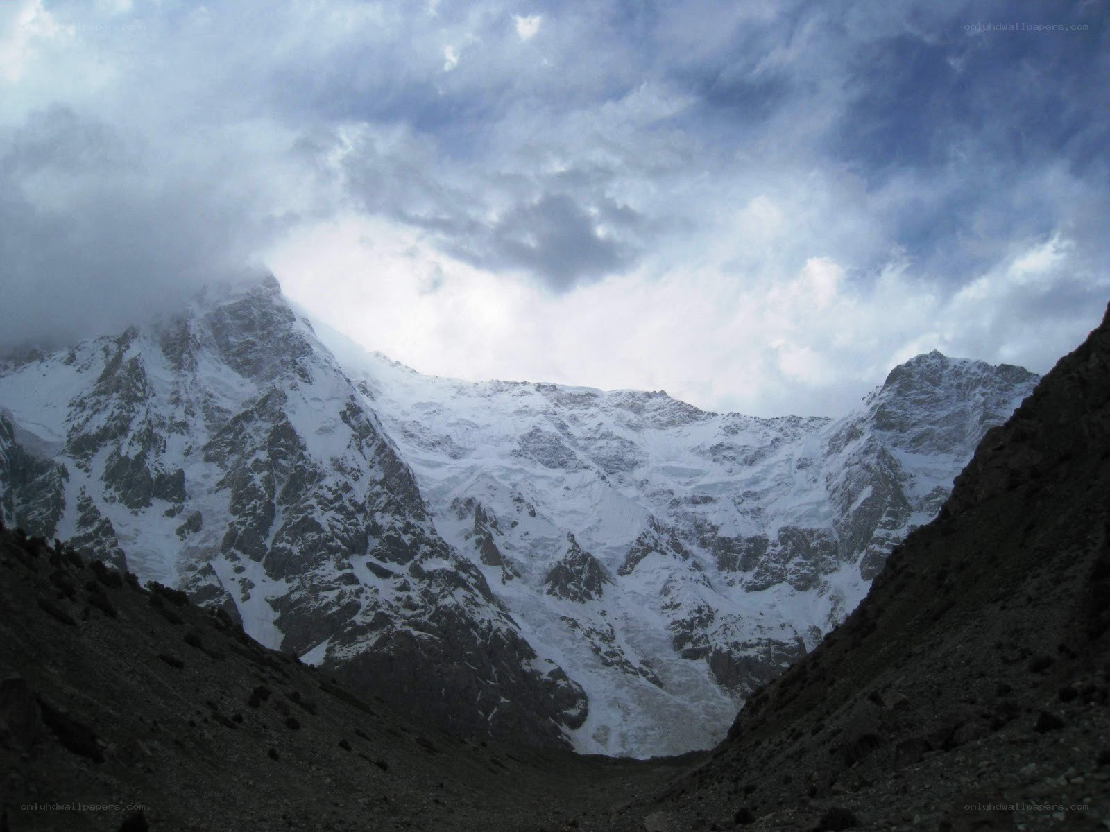 Snowy mountain peaks under cloudy sky