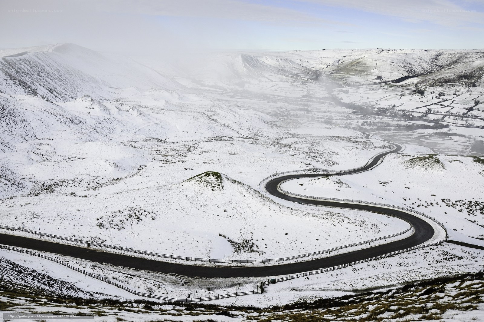 Snowy mountain road winding through valley
