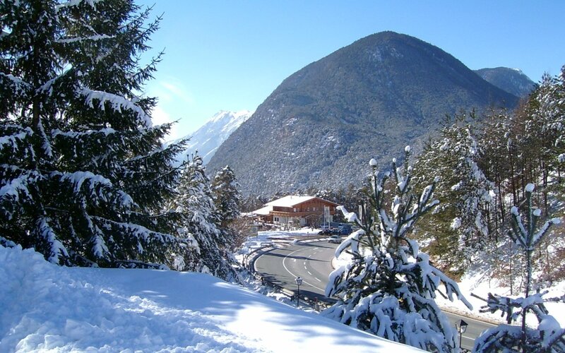 Snowy mountain road with alpine lodge