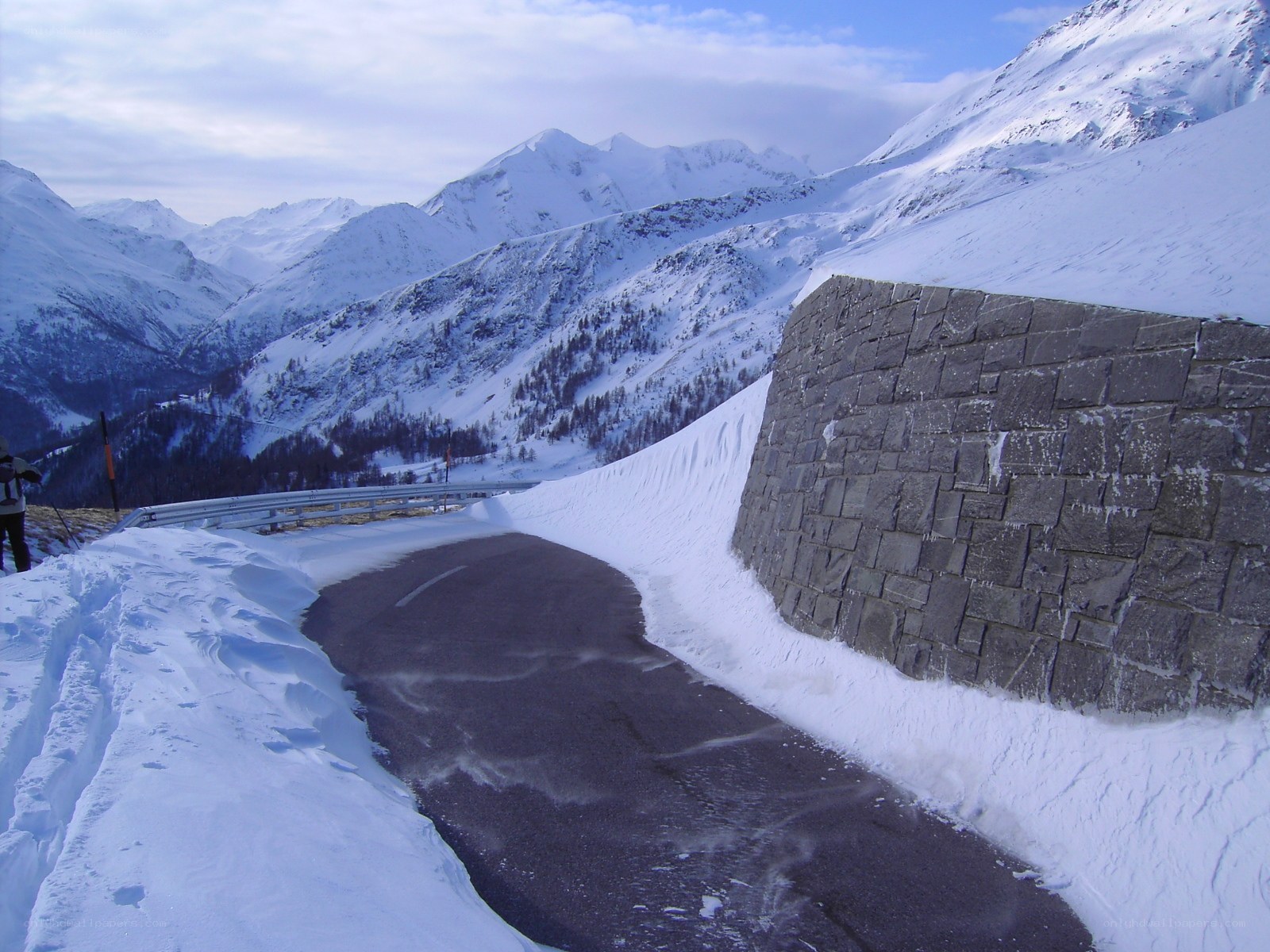 Snowy mountain road with stone wall