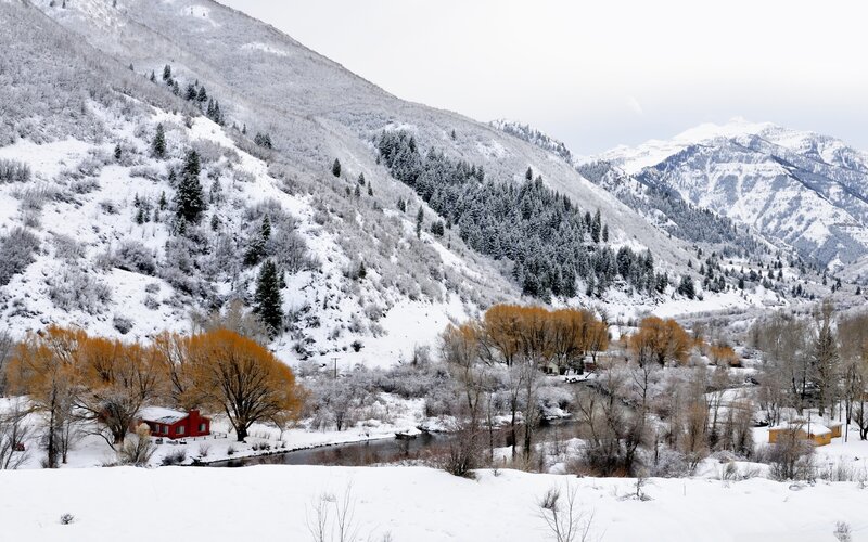 Snowy mountain valley with red cabin