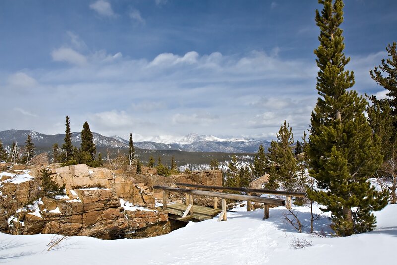 Snowy mountain vista with wooden bridge