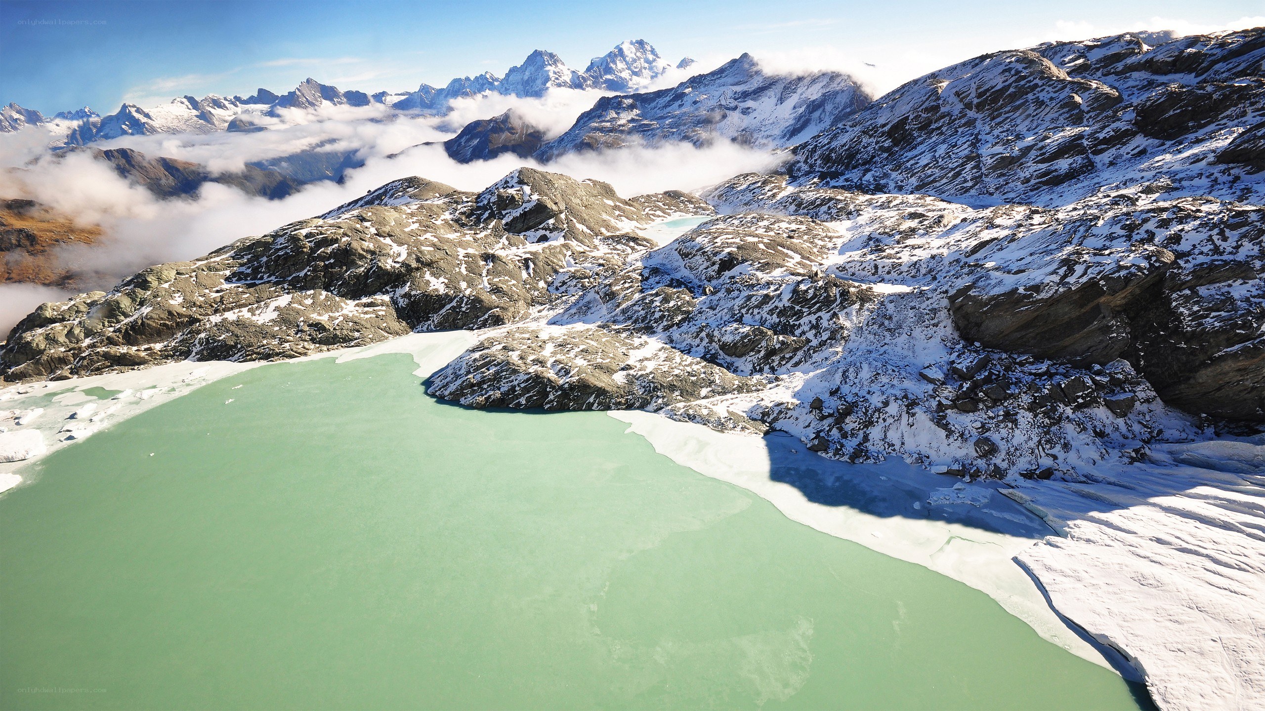 snowy mountains and green lake