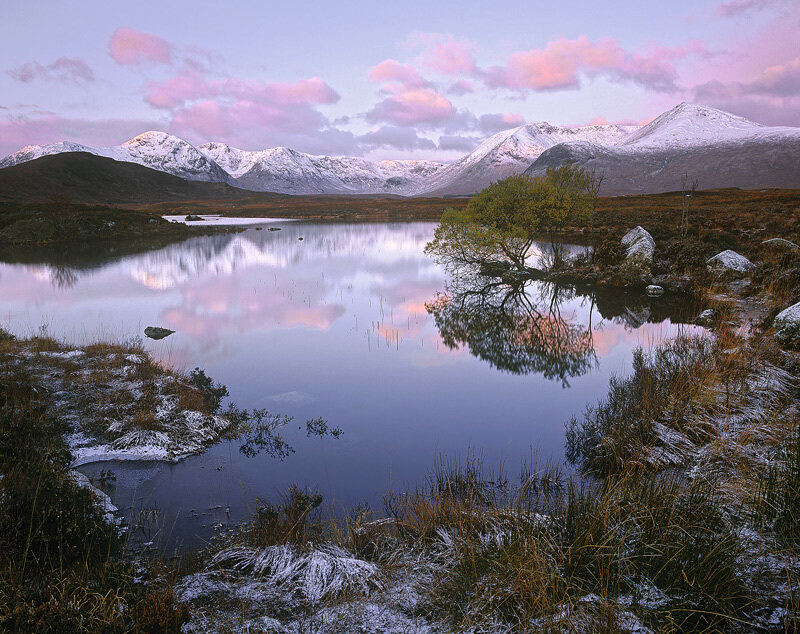 Snowy mountains reflect in a calm lake