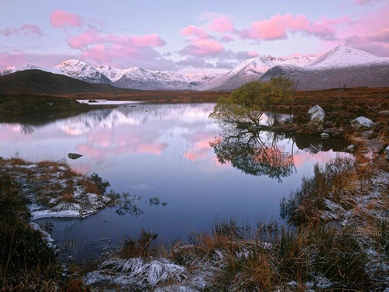 Snowy mountains reflect in a calm lake