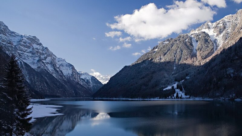 Snowy mountains reflect in calm lake