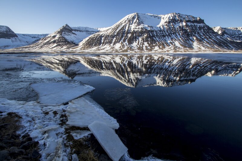 Snowy mountains reflect in calm water