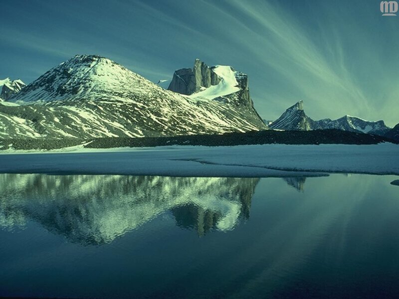 Snowy mountains reflect in calm water