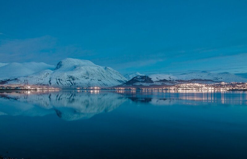 Snowy mountains reflect in calm water