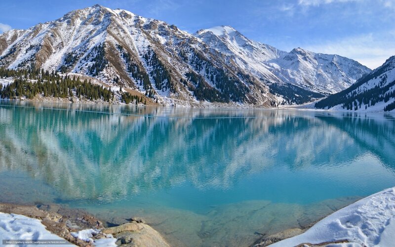 Snowy mountains reflect in turquoise lake