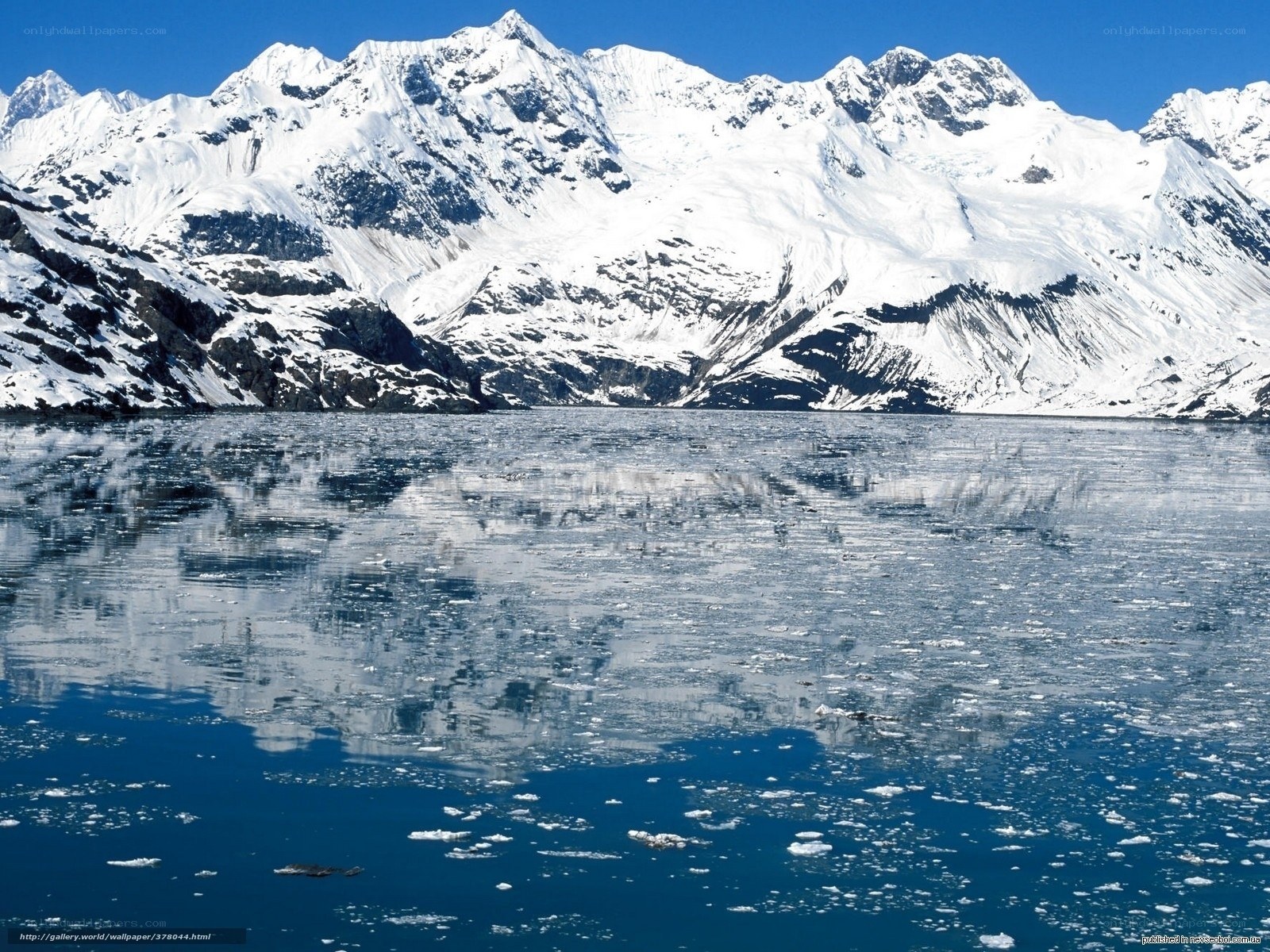 snowy mountains reflected in icy water
