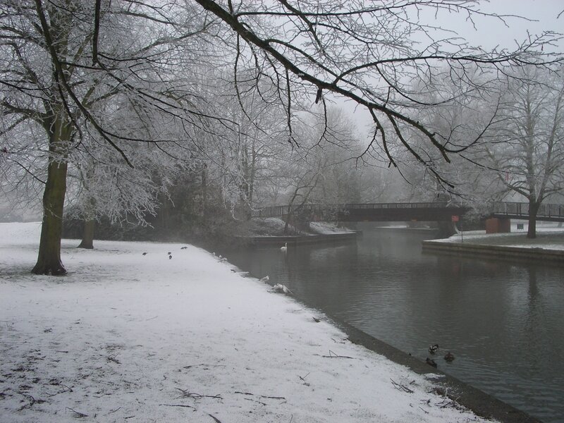 Snowy park with canal and bridge