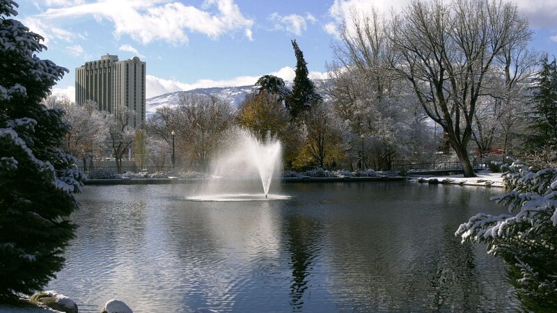 Snowy park with fountain and building