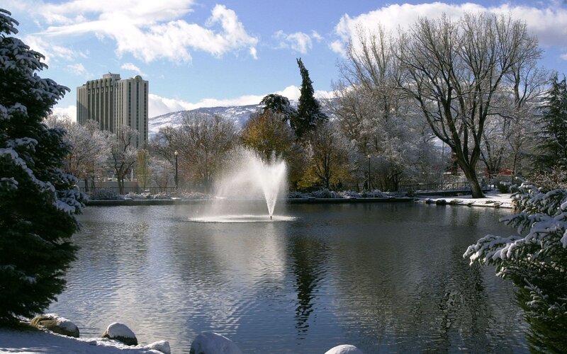 Snowy park with fountain and building