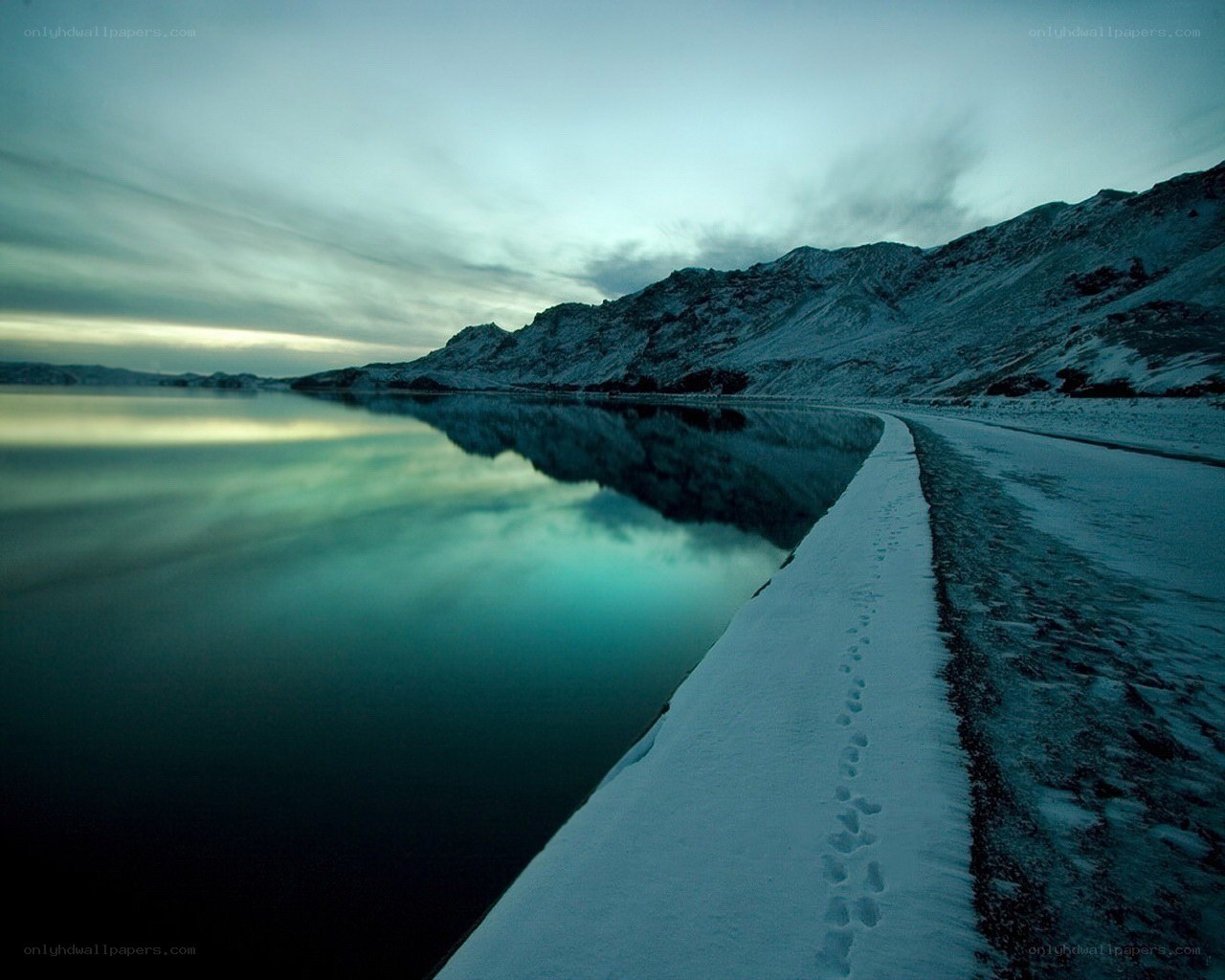 Snowy path by a calm lake