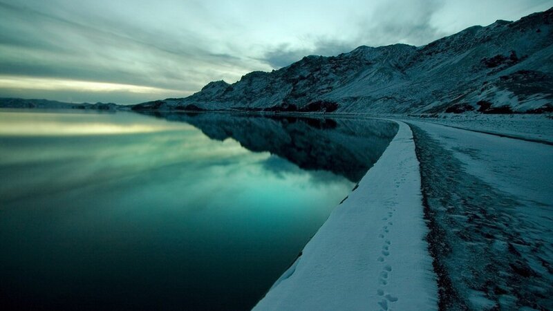 Snowy path by a calm lake