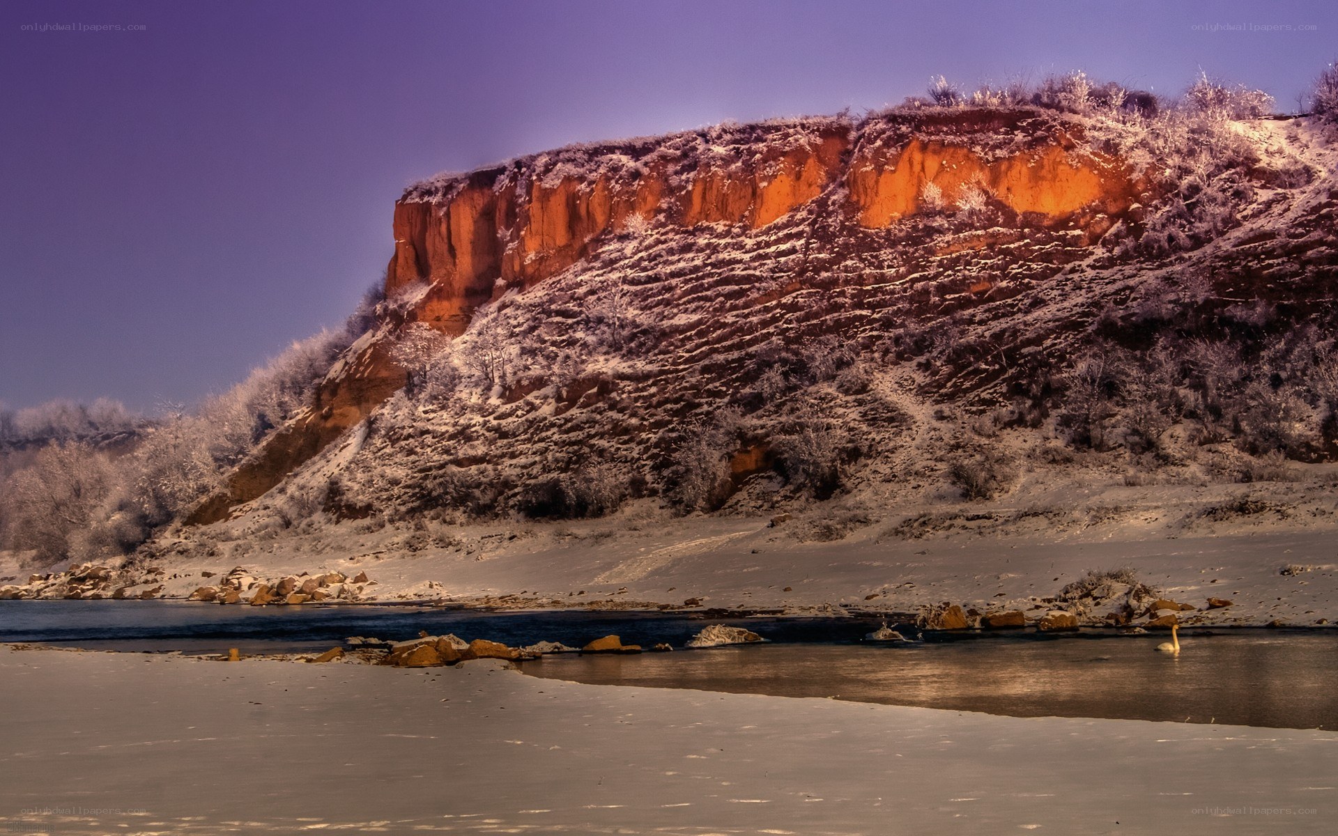 Snowy river cliff at sunset