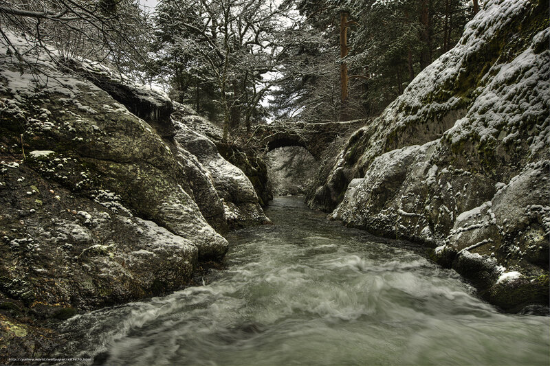 Snowy river gorge with stone bridge