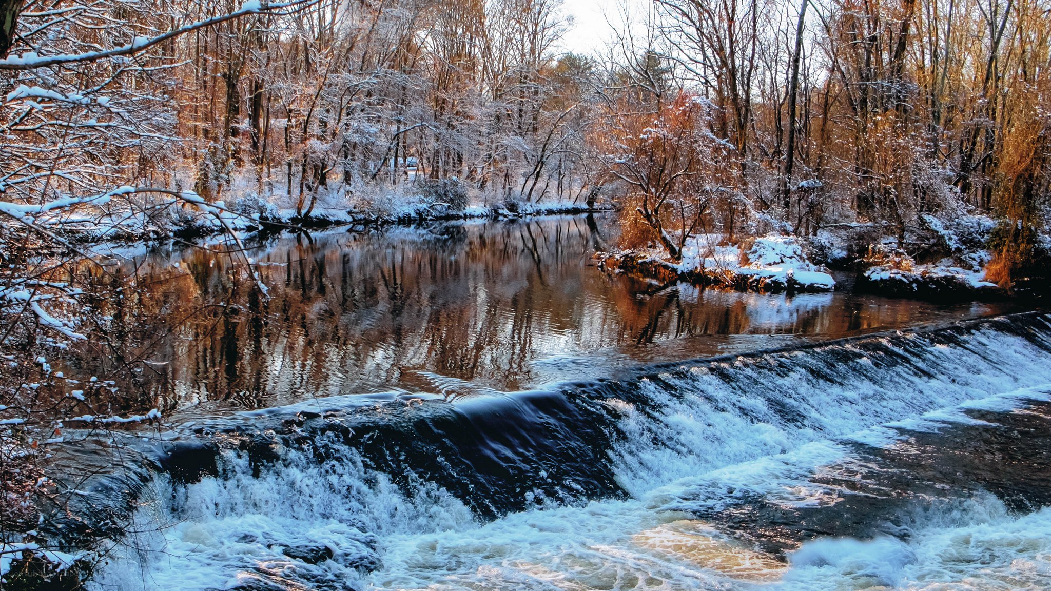 Snowy river with small waterfall