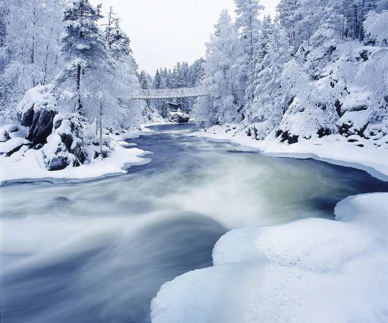 Snowy river with suspension bridge