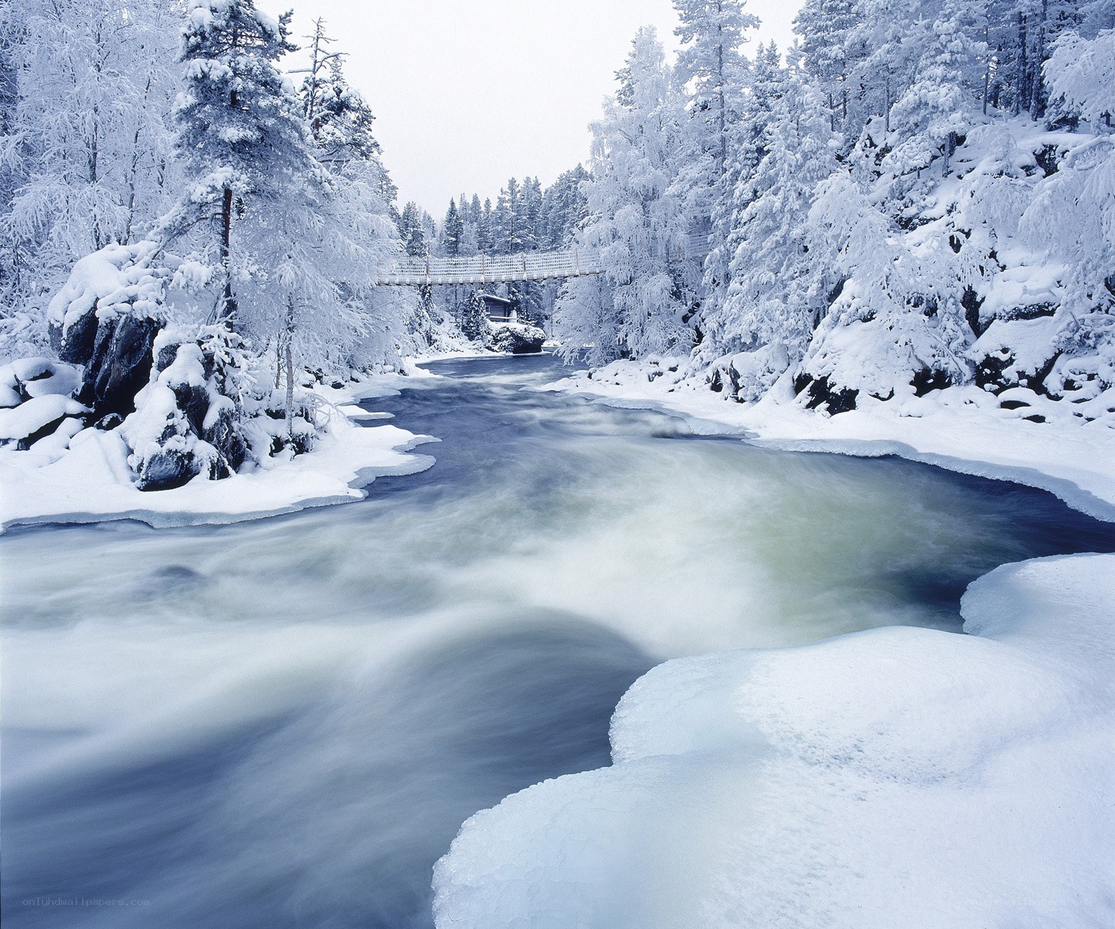 Snowy river with suspension bridge